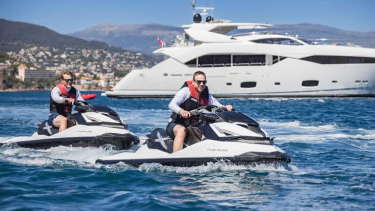Guests on jet skis in front of a yacht