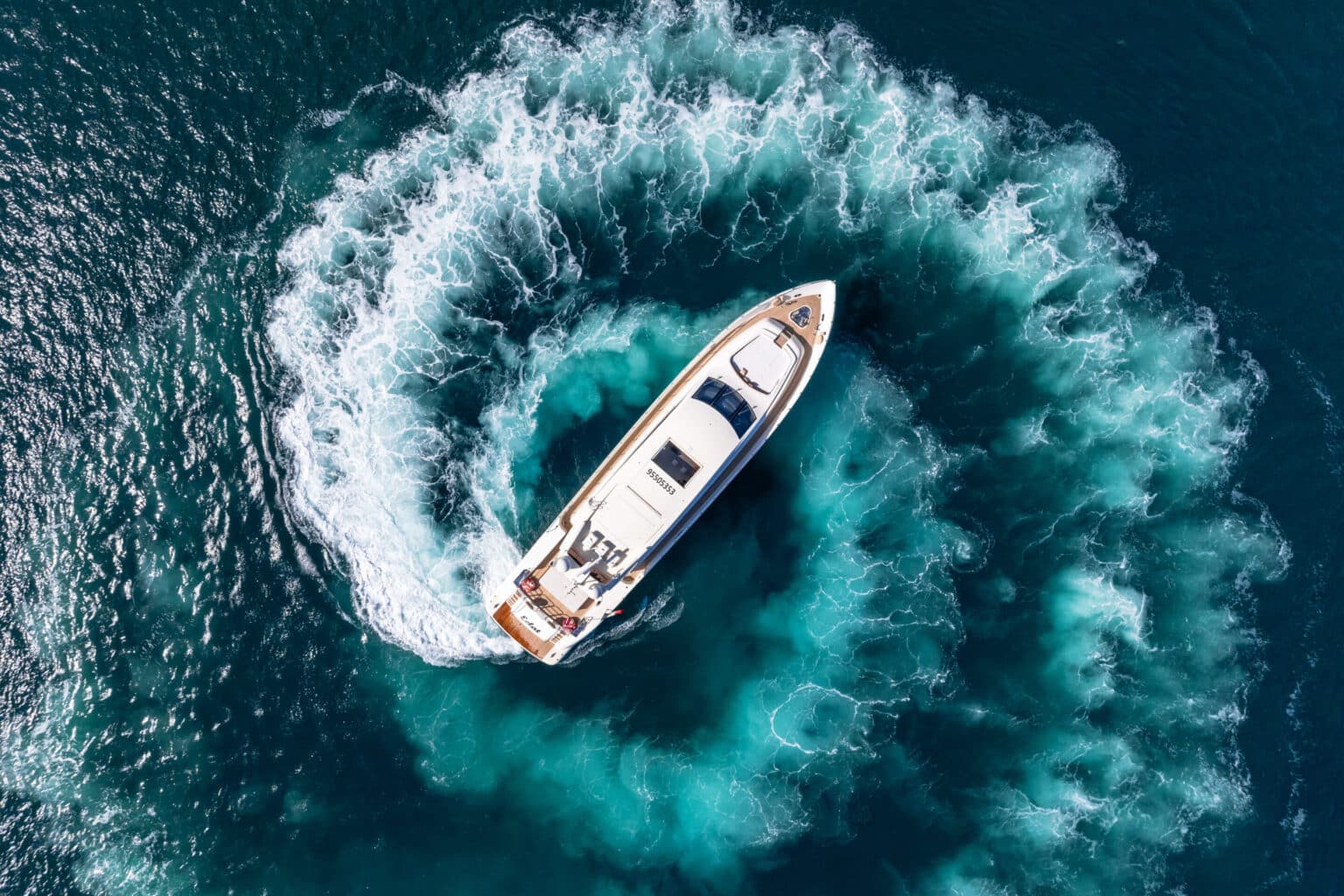 Aerial view of a yacht turning in its wake