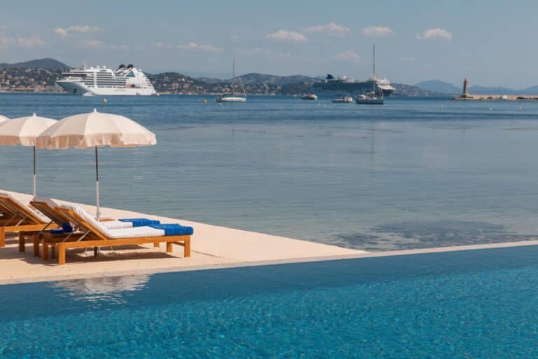 Two sun loungers and parasols by a pool